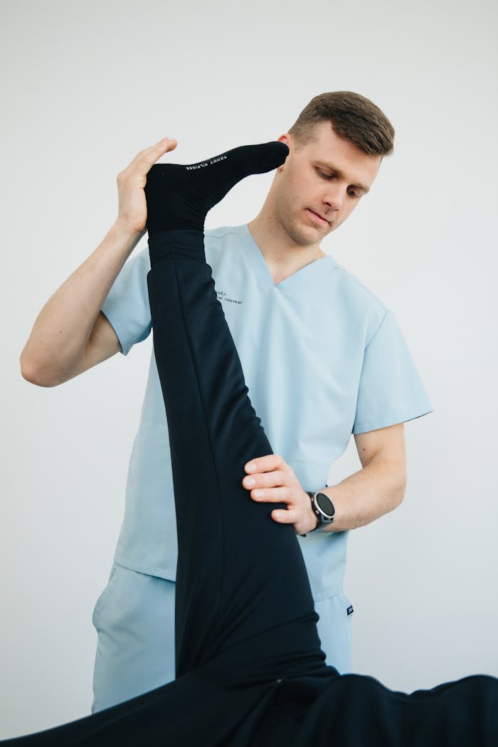 Professional physiotherapist helping a patient with leg exercises in a clinic setting.